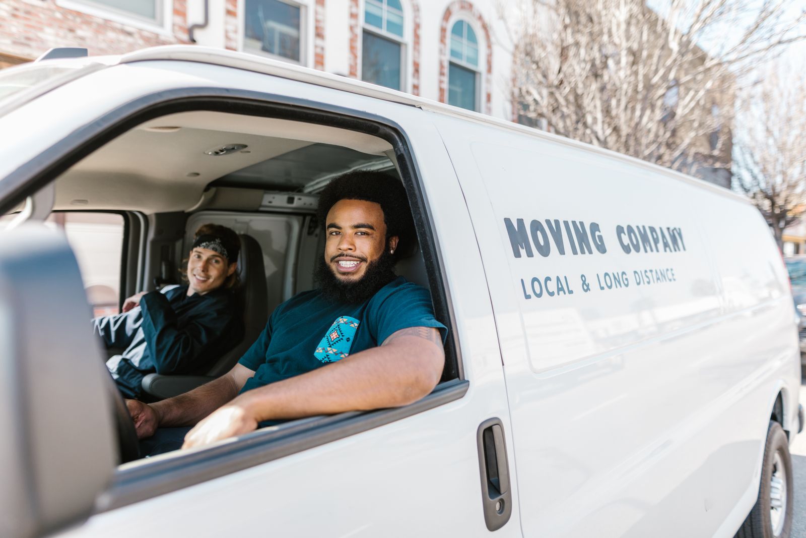 Two removalists smiling from their company van