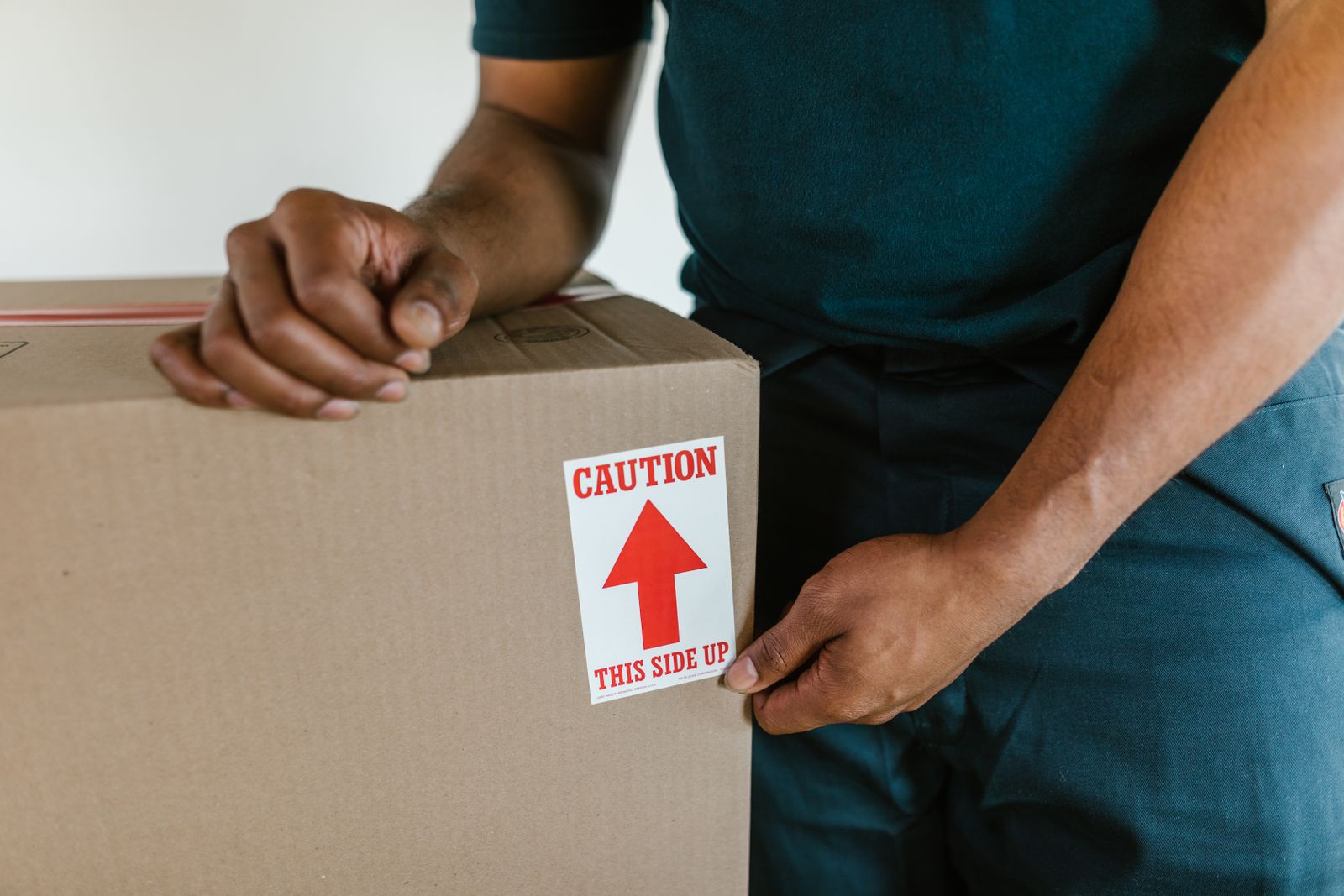 Removalist carefully handling a box marked this side up